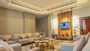 Una sala de estar moderna con un sofá, sillones, una mesa de centro y un televisor de pantalla plana montado en una pared con textura.