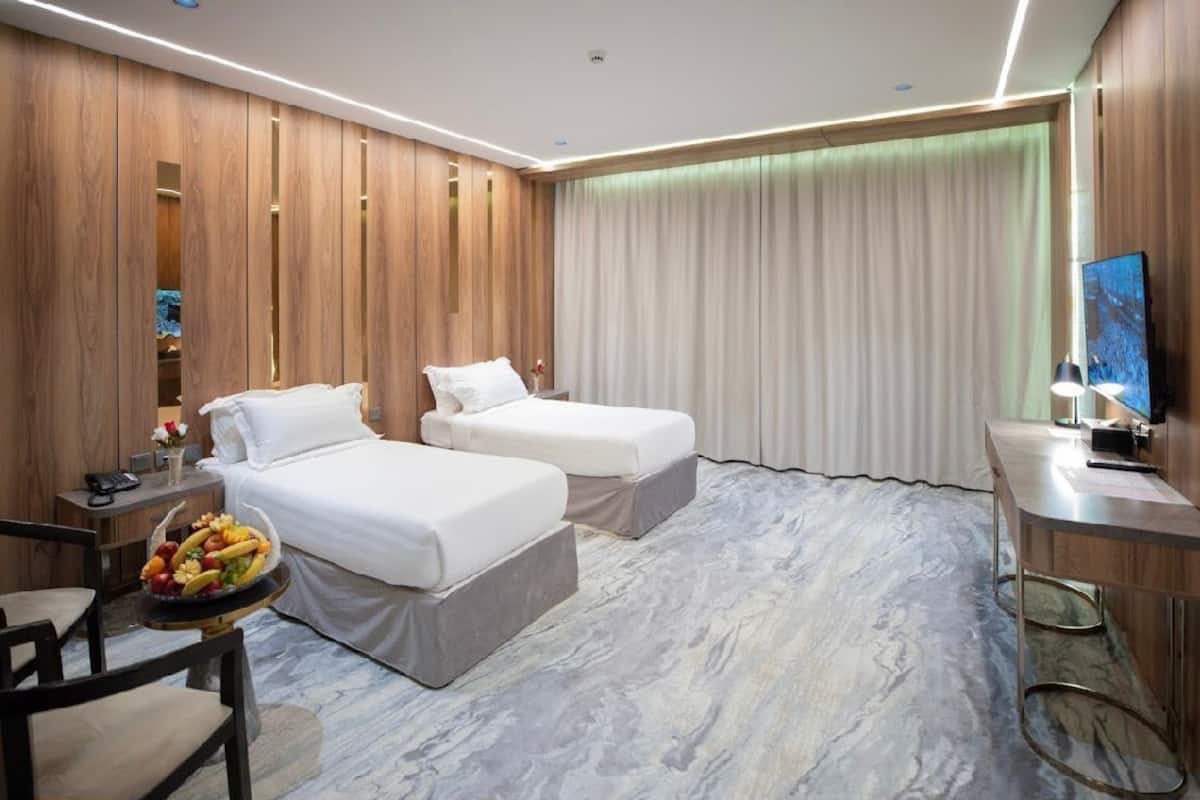 Una habitación de hotel con dos camas, un escritorio, una silla y un frutero.