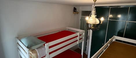 Ein Zimmer mit Etagenbetten, Holzboden, einer Kristallleuchtre und einer grünen Wand.