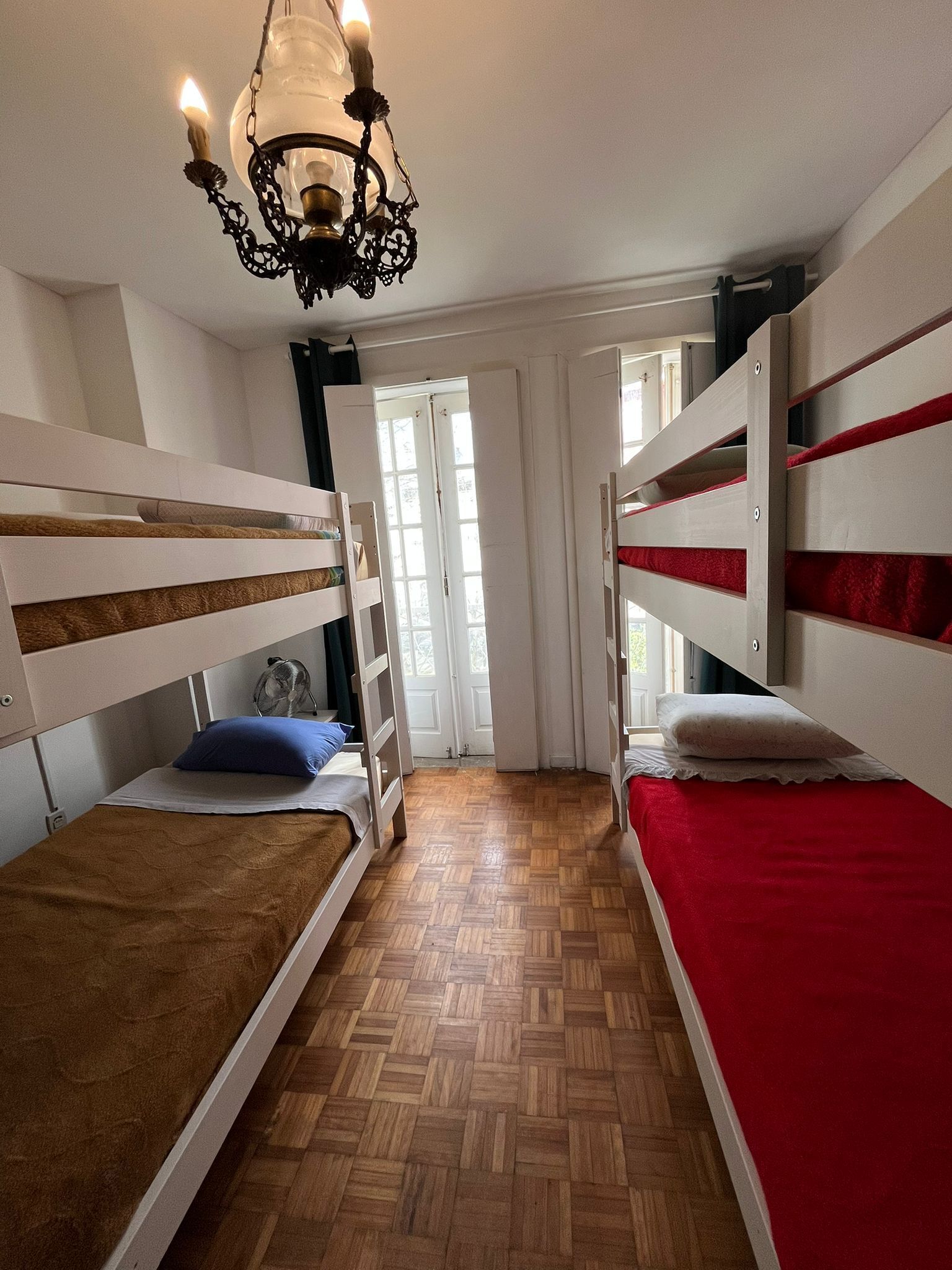 Una habitación con literas, un candelabro y una puerta que da a un espacio luminoso.