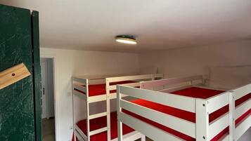 A room with bunk beds, a door, and a ceiling light.