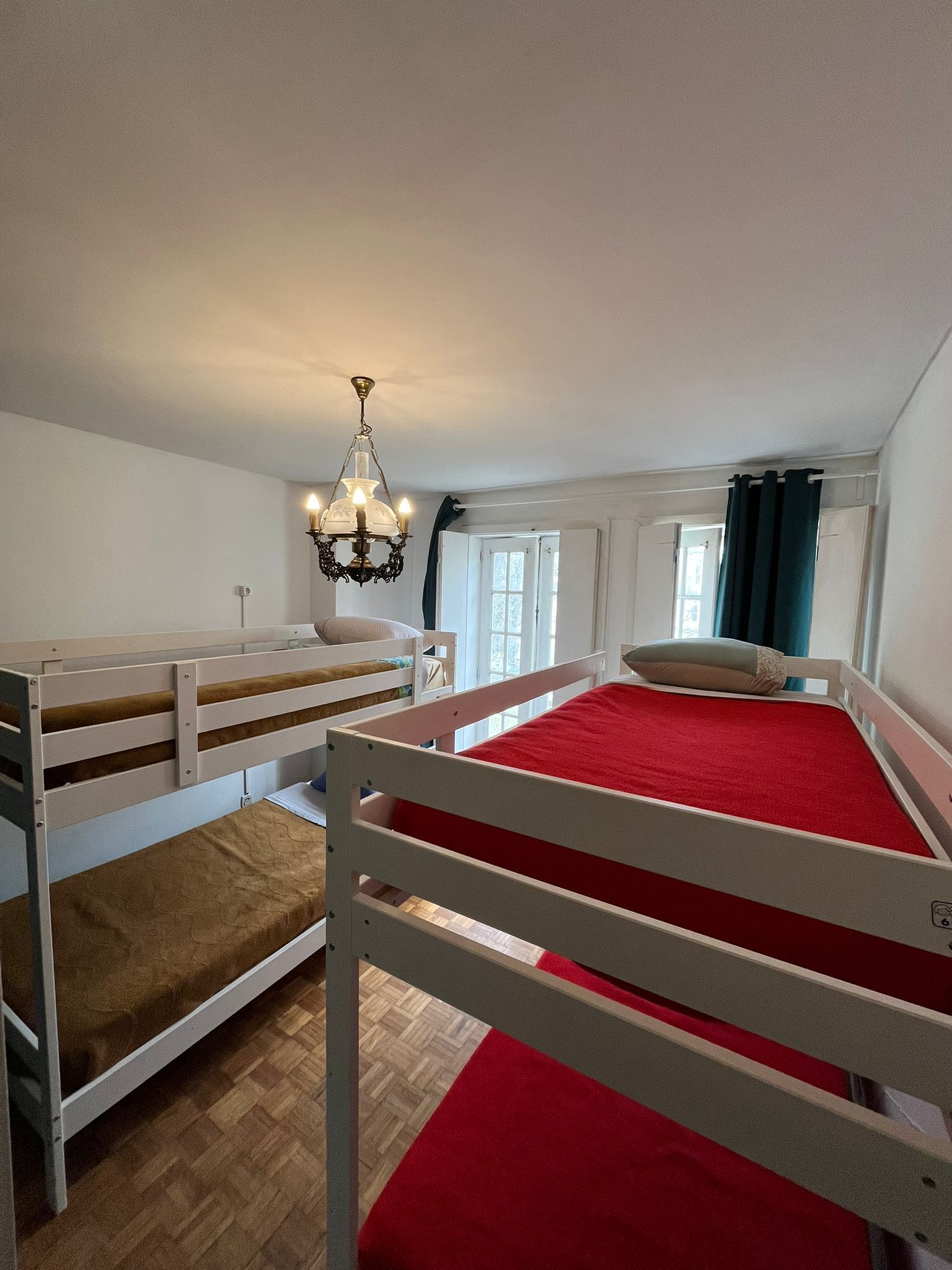 A room with bunk beds, a chandelier, and a window with curtains.