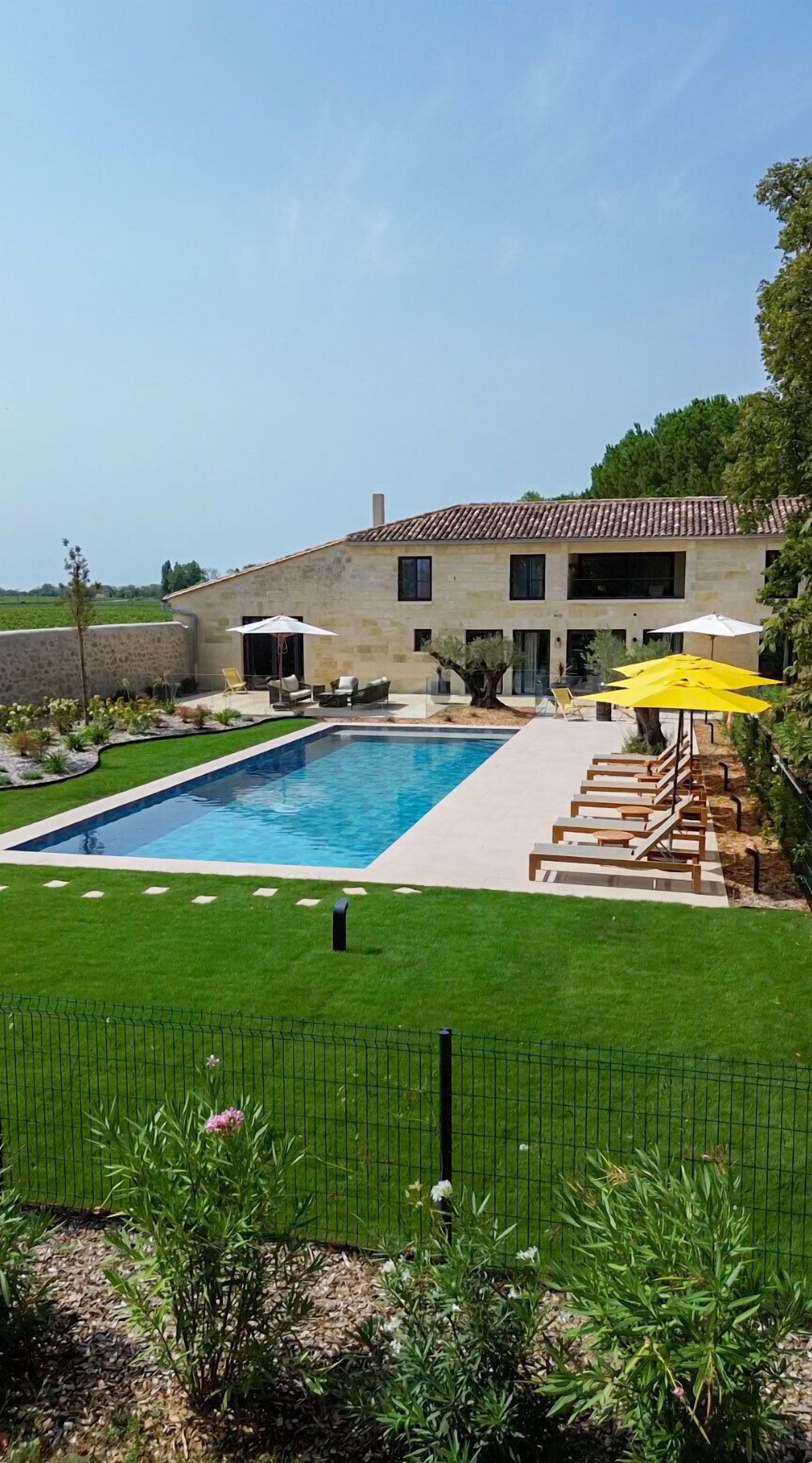 Une maison moderne dot ée d’une piscine, d’un espace salon extérieur et d’une pelouse bien entretenue.