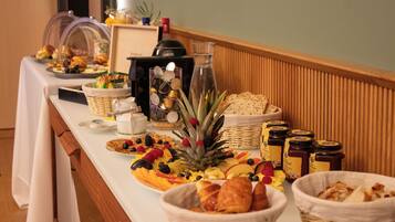 Una mesa de buffet con diversos alimentos, como frutas, pasteles y salsas.