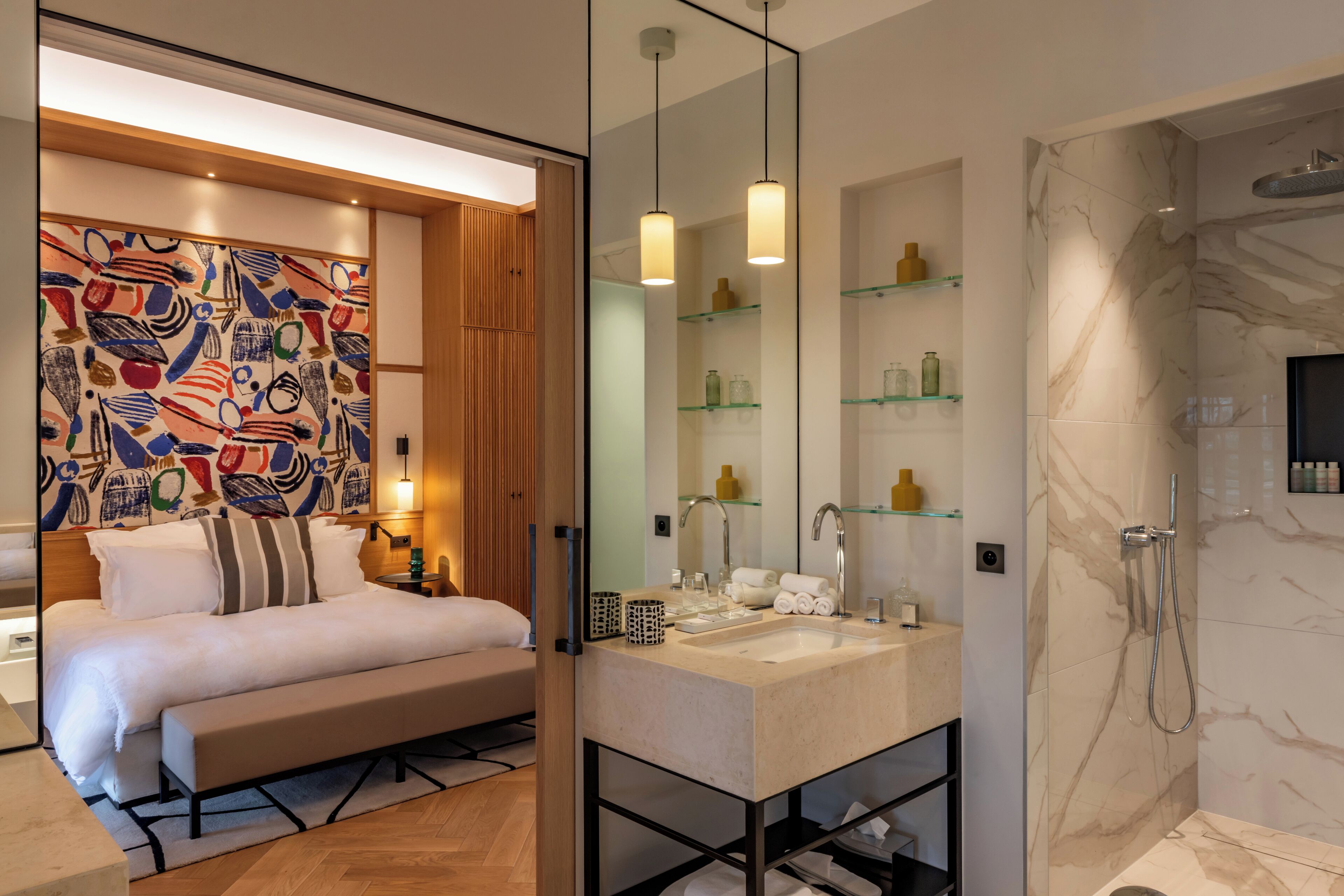 Une chambre à coucher moderne avec un grand lit, des tables de chevet et un tableau abstrait aux couleurs vives accroché au mur.