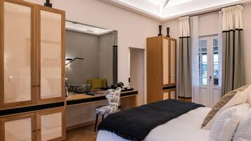 Ett modernt hotellrum med en stor säng, ett skrivbord med en stol, en garderob och en stor spegel.