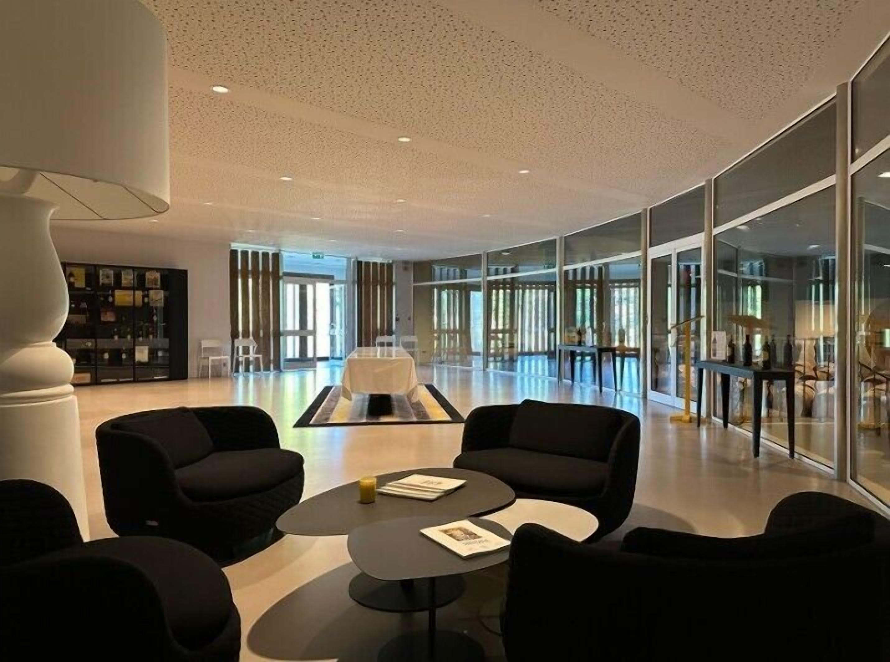 A modern lobby with black sofas, a central table, and glass walls.