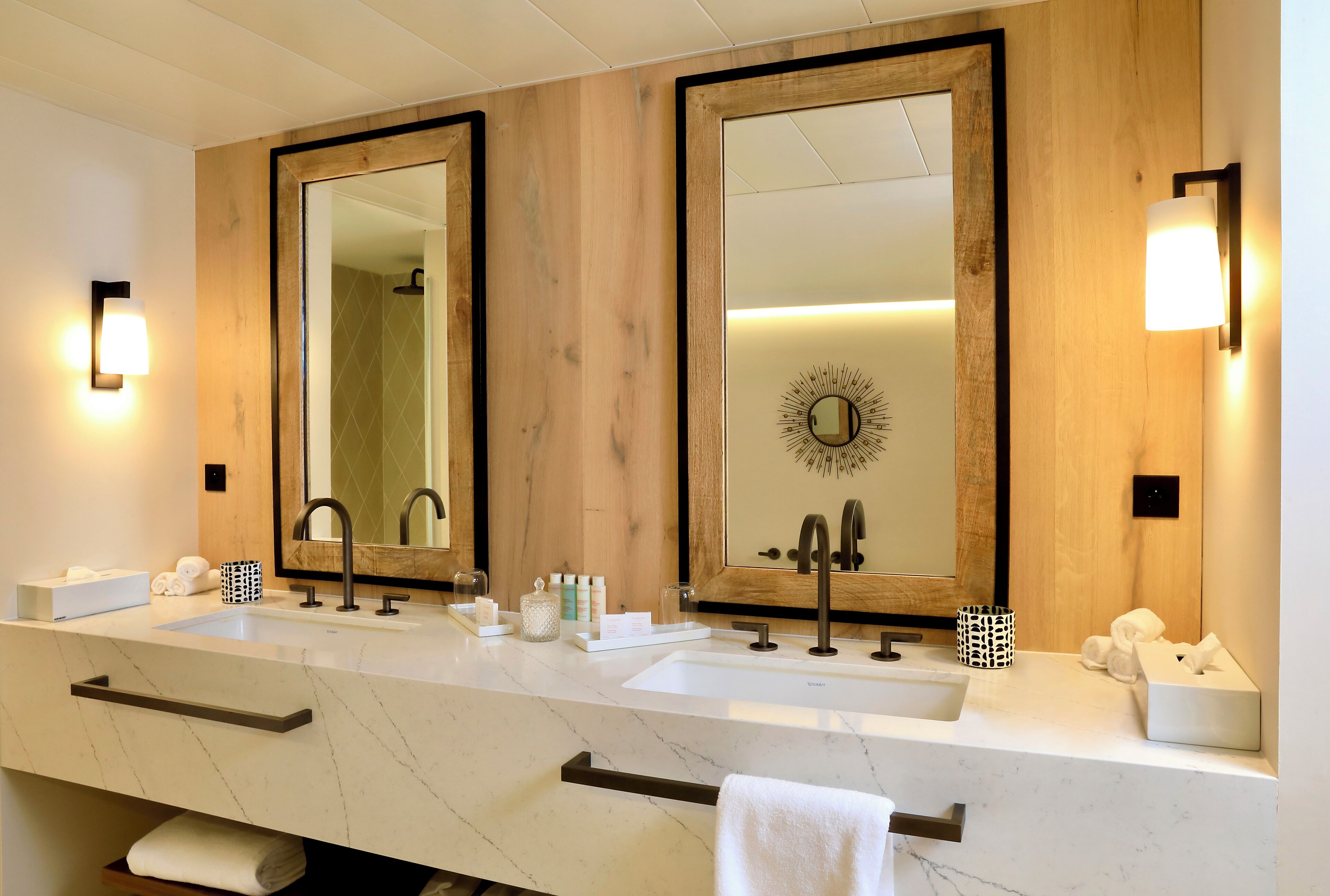 A modern bathroom with two sinks, large mirrors, and a wooden panel wall.