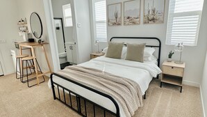 Ein Schlafzimmer mit einem Bett, Nachttischen, einem Deckenventilator und Kunstwerken an den Wänden.