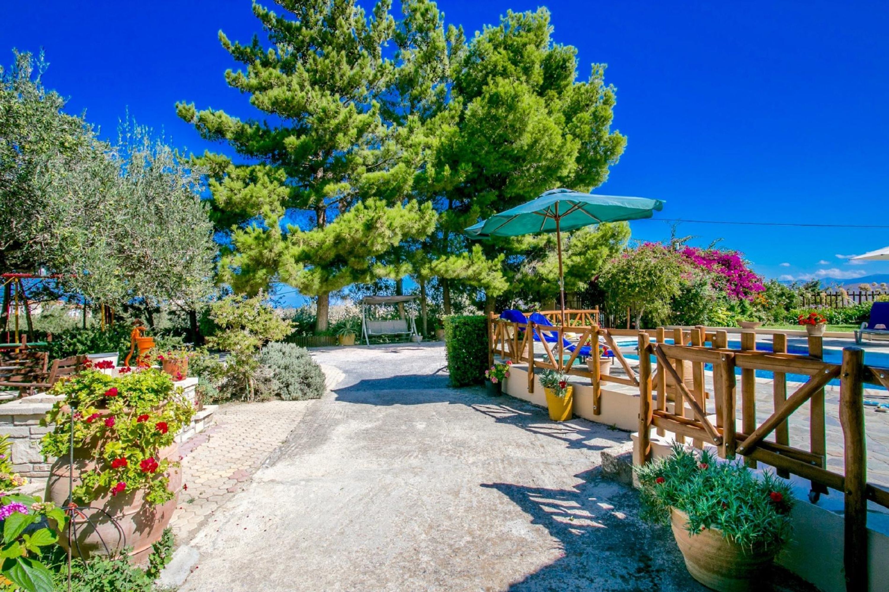A pool area with a wooden deck, a swing set, and a large tree.