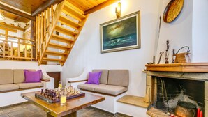 Ein gemütliches Wohnzimmer mit einer Holztreppe, einem Kamin und einem Schachbrett auf einem Tisch.
