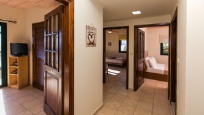 Un couloir avec une porte en bois, un téléviseur et un lit à l’arrière-plan.