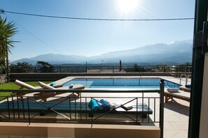 Ein Swimmingpool mit Liegestühlen und Blick auf Berge.