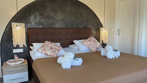 A neatly made bed with floral pillows, a brown headboard, and two bedside tables with lamps. - Villa De La Vita Alykes (Zakynthos)