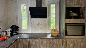 A kitchen with a built-in oven, a microwave, and a large screen TV mounted above the counter. - Villa De La Vita Alykes (Zakynthos)