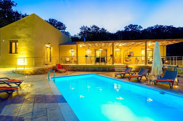 A swimming pool with lounge chairs and a covered patio area.