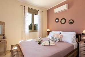 A bedroom with a bed, bedside tables, a mirror, and an air conditioning unit.
