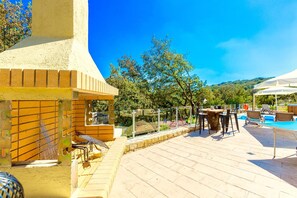 An outdoor pool area with lounge chairs and a barbecue setup.