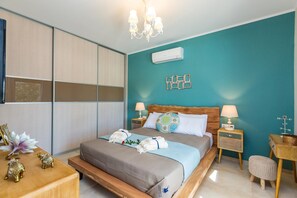 Un dormitorio con cama, mesitas de noche, un banco de madera y un aire acondicionado instalado en la pared.