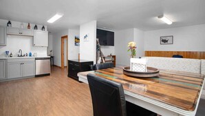 A modern kitchen with grey cabinets, a wooden dining table, and a black chair. - Meadow Rue Retreat • Aurora Views Near Fairbanks (North Pole, AK)