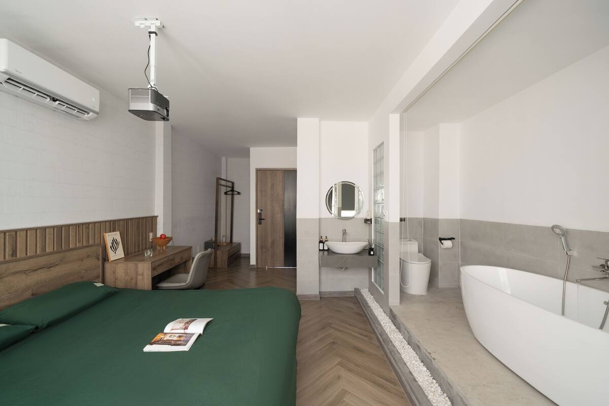 Ein modernes Hotelzimmer mit einem Bett, einem Schreibtisch, einem Badezimmer mit Badewanne und Dusche.