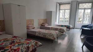 Una camera del dormitorio con tre letti, un armadio e una sedia.