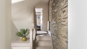 A staircase with a potted plant, a stone wall, and a door leading to another room. - Ferry View Cottage in Bowness-on-windermere (Windermere)