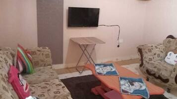 A living room with two patterned sofas, a small table, and a television mounted on the wall.