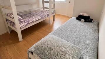 Um quarto com uma cama de solteiro, uma cama individual, uma janela com persianas e um radiador.