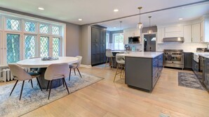 Una cocina moderna con una isla central, electrodomésticos integrados y un comedor con una mesa redonda y sillas.