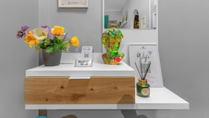 Ein weißer Tresen mit einer Blumenvase, einem gerahmten Kunstwerk und einem kleinen Tisch mit Kerzenhalter.