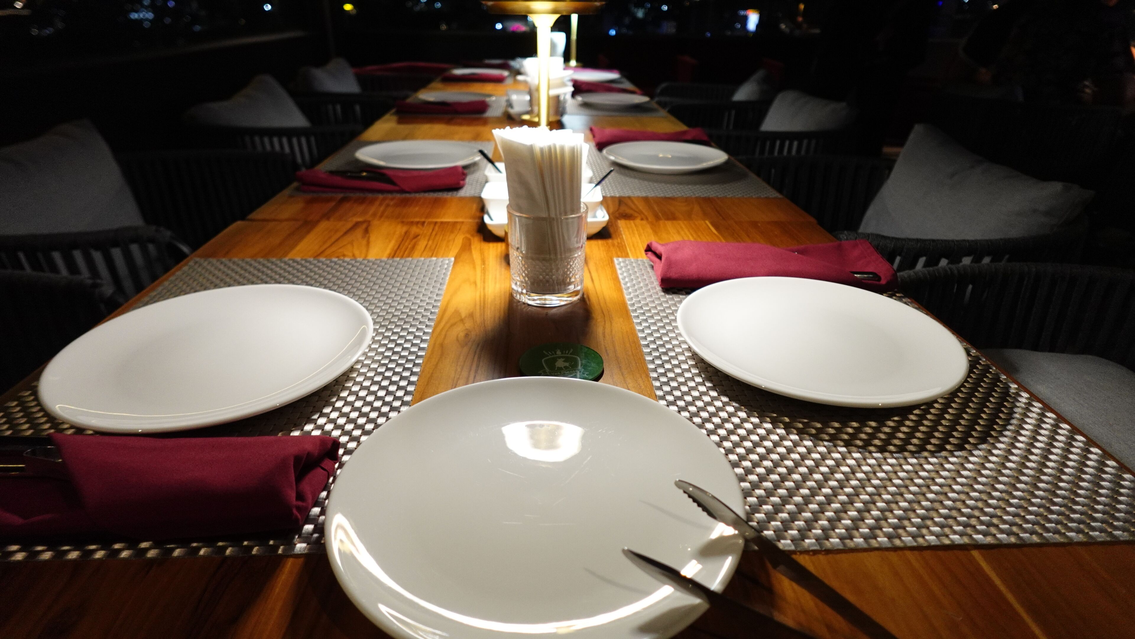 Une table à manger dressée pour quatre personnes, avec de l’assiette blanche, des couverts et un chandelier en guise de décoration centrale.