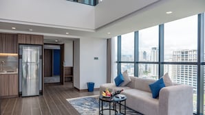 Un salón moderno con sofá, mesa de centro y vistas de la ciudad a través de grandes ventanales.