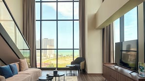 Una sala de estar moderna con un ventanal grande, un sofá, una mesa de centro, un televisor y una silla.