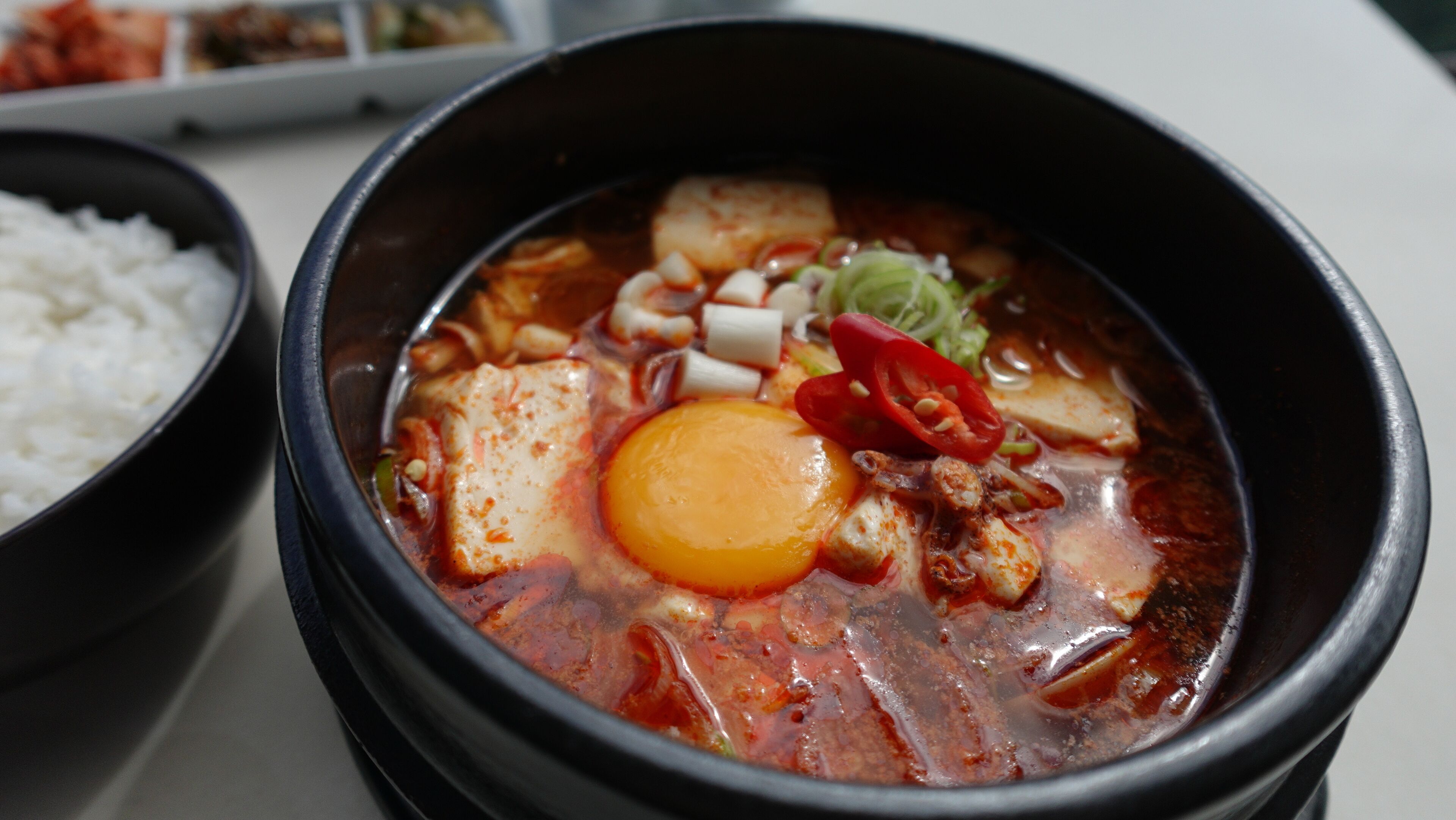 Eine Schüssel scharfe Suppe mit Tofu, Ei und Gemüse.