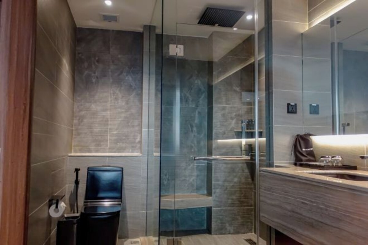 A modern bathroom with a glass shower enclosure, a sink with a mirror, and a towel rack.