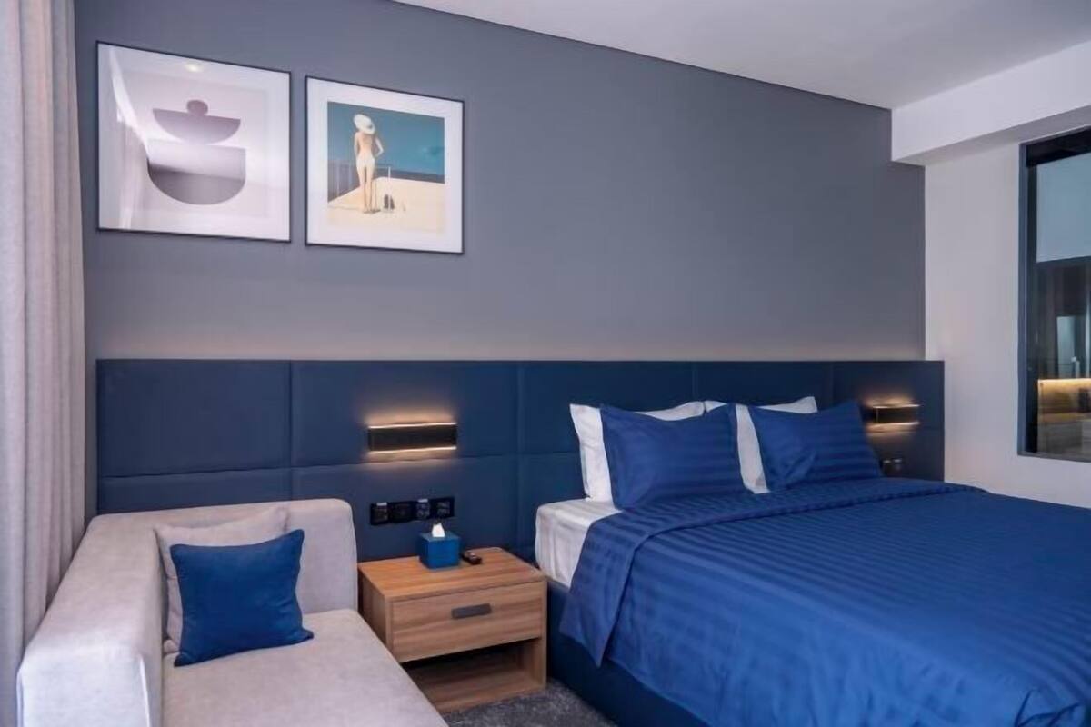 Ein modernes Hotelzimmer mit Bett, Sofa, Nachttisch und Wandleuchten.