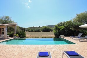 A swimming pool with lounge chairs and a covered seating area.