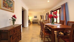 Un comedor con una mesa y sillas de madera, un aparador de madera y un cuadro en la pared.