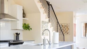 A modern kitchen with a central island, bar stools, and a staircase. - NEW BUILD Pet Friendly I Highlands I RiNo I Dwntwn (Denver)