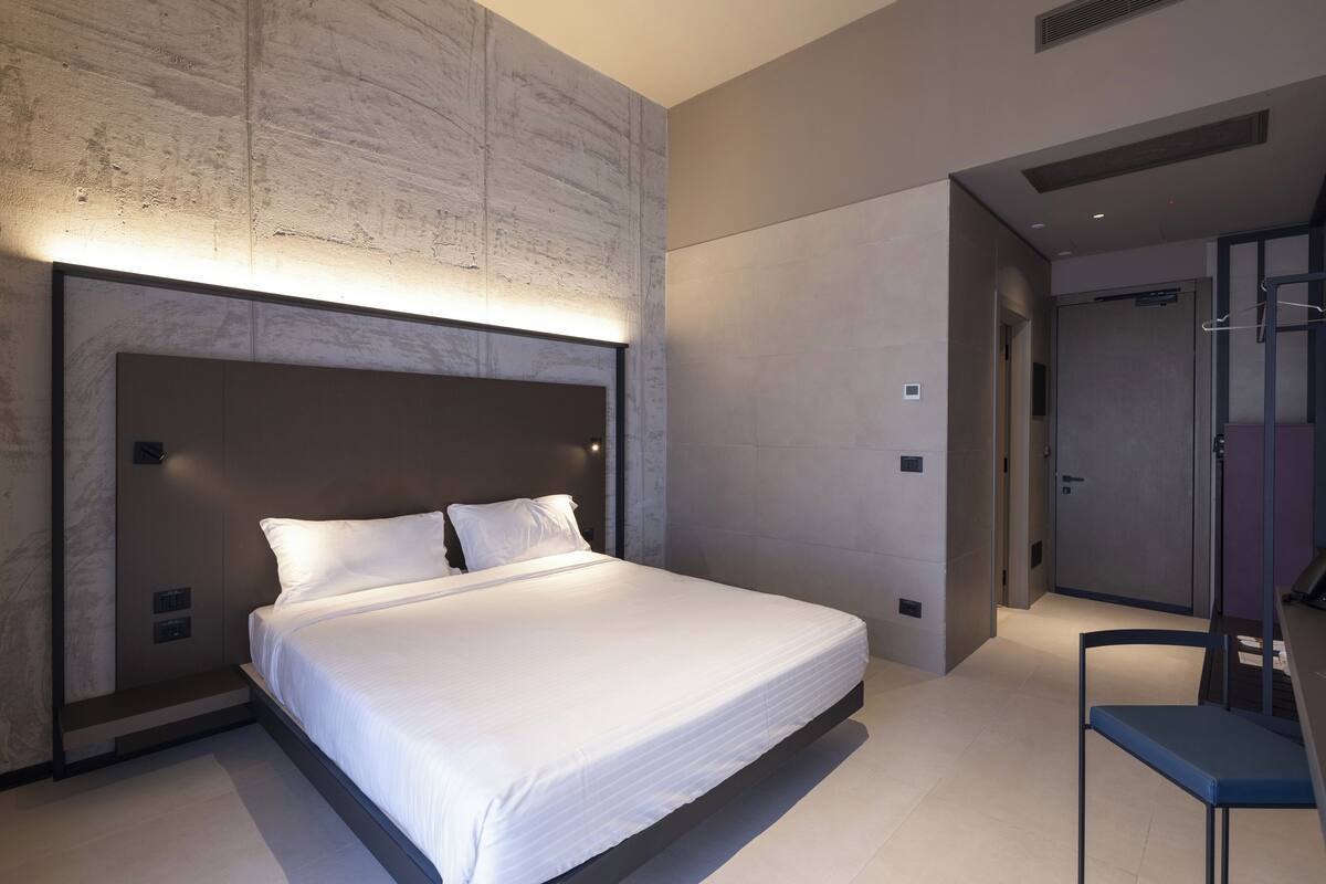 A modern bedroom with a large bed, a built-in headboard, and a walk-in closet.
