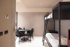 Een moderne kamer met een stapelbed, een ronde tafel met stoelen en een klein bureau.