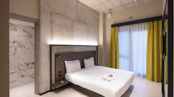 Habitación de hotel moderna con una cama grande, pared de mármol y vista de la ciudad a través de cortinas.