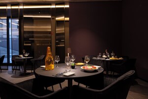 Een eetgedeelte met ronde tafels, stoelen en een fles champagne.