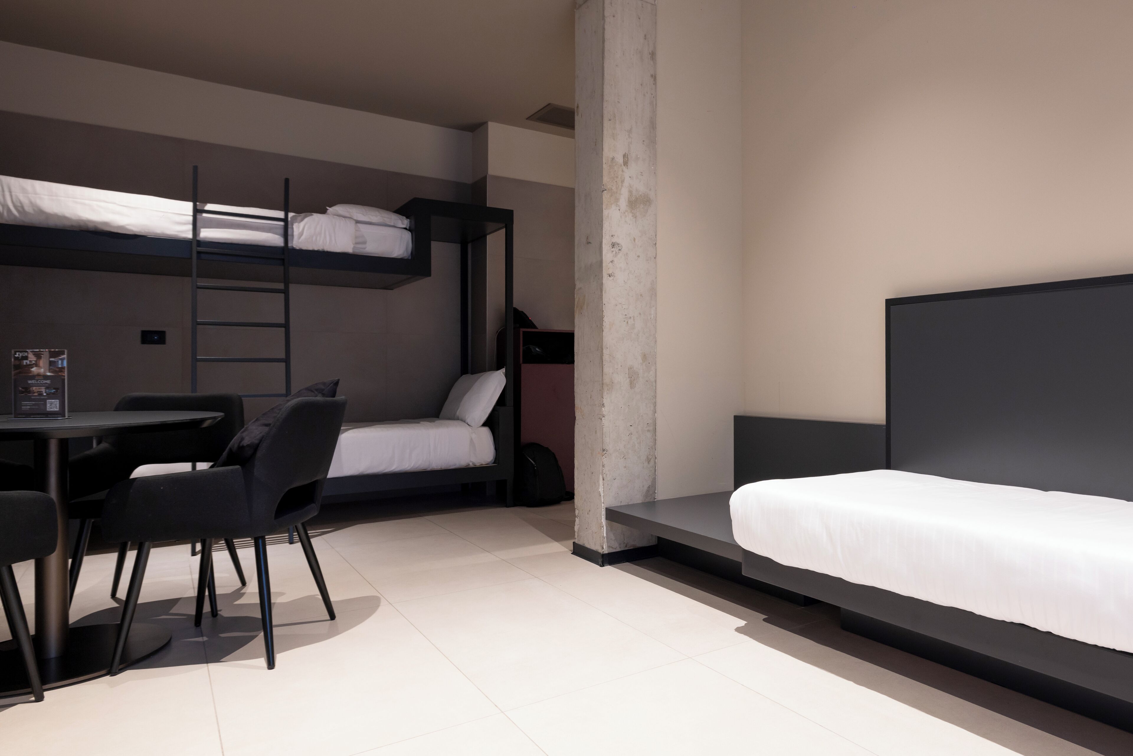 A modern room with bunk beds, a desk, and chairs.