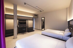 Een moderne hotelkamer met twee bedden, een bureau, een televisie en een grote spiegel.