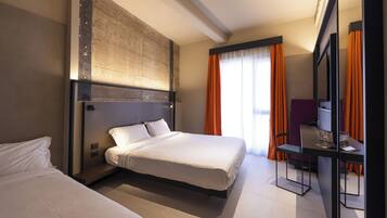 Une chambre d’hôtel moderne avec un grand lit, un bureau avec une chaise et un grand miroir.