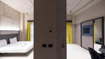 A modern hotel room with a large bed, a TV mounted on the wall, and a desk with a chair.