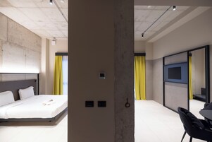 Camera d'hotel moderna con un letto grande, una TV a muro e una scrivania con una sedia.