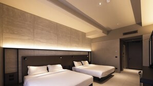 Une chambre d’hôtel moderne équipée de deux lits, d’un bureau et d’un grand luminaire fixé au mur.